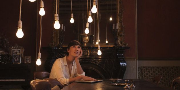 Woman sitting at table with hanging lightbulbs