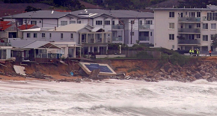 Officials stand near a swimming pool and houses that suffered damage after severe weather.