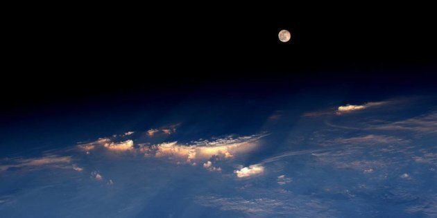 Astronaut Jeff Williams took this photograph of the rare Strawberry Moon emerging from the clouds while orbiting Earth from the International Space Station on Tuesday. 