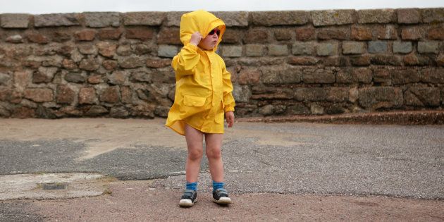 Young boy wearing a yellow jacket at the Engliash seaside, on a windy day.