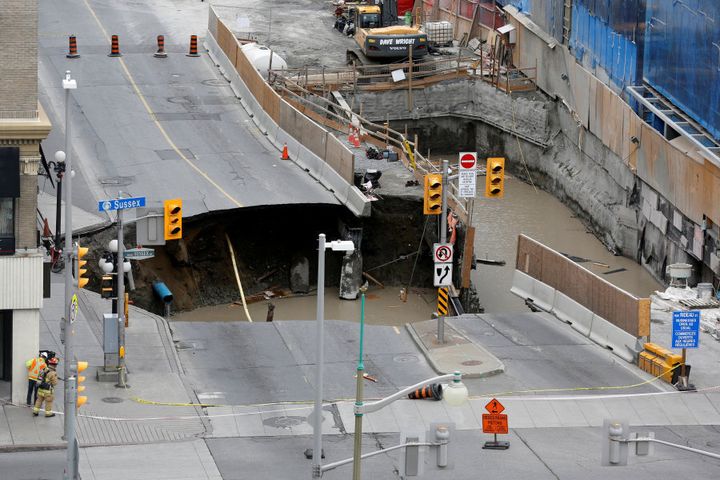 Workers look at a large sinkhole in Ottawa, Ontario, Canada.