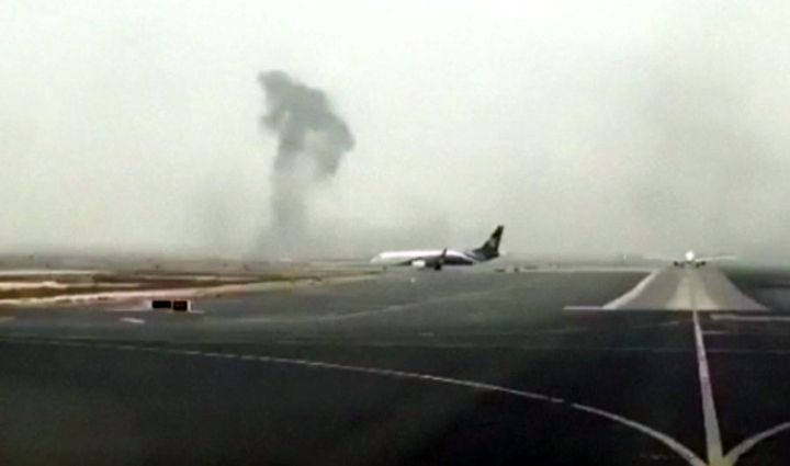 Smoke rises in the distance from the crash-landed Emirates flight