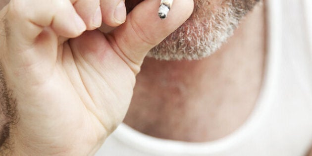 Closeup view of a man smoking a marijuana joint. **Dramatization - no illegal narcotics were used in the making of this photograph**