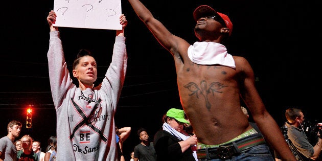 A protestor holds a sign showing a book and a gun on Old Concord Rd. on Tuesday night, Sept. 20, 2016 in Charlotte, N.C. A protest began on Old Concord Road at Bonnie Lane, where a Charlotte-Mecklenburg police officer fatally shot a man in the parking lot of The Village at College Downs apartment complex Tuesday afternoon. The man who died was identified late Tuesday as Keith Scott, 43 and the officer who fired the fatal shot was CMPD Officer Brentley Vinson. Earlier a woman who said she is Scott's daughter claimed on a live-streamed video on Facebook that Scott was unarmed when he was shot. In the video, the woman said her father was sitting in his car reading a book and waiting for the school bus to drop off his son. She claimed that her father was tasered and then shot four times, and that he was disabled. (Jeff Siner/Charlotte Observer/TNS via Getty Images)