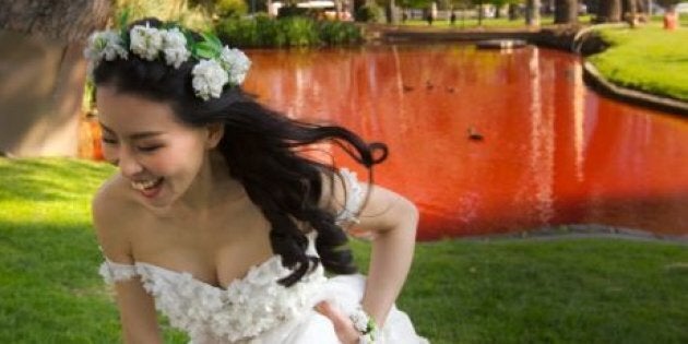 A bride poses alongside the red lake.