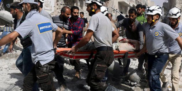 A civil defense member carries out a search and rescue operation over the wreckage of collapsed buildings in Aleppo.