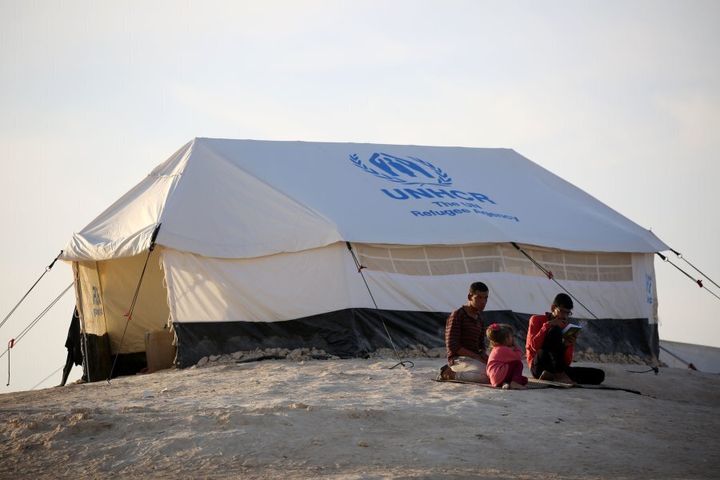 Youth sit outside a UNHCR tent at a refugee camp housing Iraqi families who fled fighting in the Mosul area