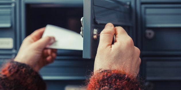 Closeup on a woman's hand as she is getting her post out of her letterbox