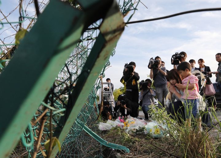 保育園児らの列に乗用車が突っ込んだ事故で、フェンスが大きく変形した現場に花を手向ける人たち＝5月8日午後、大津市