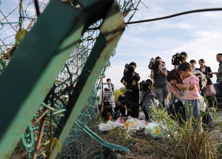 保育園児らの列に乗用車が突っ込んだ事故で、フェンスが大きく変形した現場に花を手向ける人たち＝5月8日午後、大津市