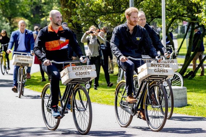 Former Dutch serviceman and athlete Dennis van der Stroom (left) and Prince Harry (right) ride bikes during the presentation