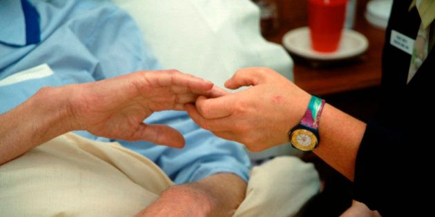 Hospice worker holding elderly man's hand UK. (Photo by: Photofusion/UIG via Getty Images)