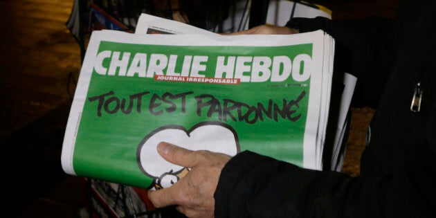 A seller of newspapers installs in shelf, several Charlie Hebdo newspapers at a newsstand in Nice southeastern France, Wednesday, Jan. 14, 2015. On front page reading