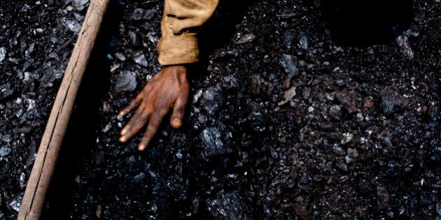 JAINTIA HILLS, INDIA - APRIL 16: Thirty eight-year-old Prabhat Sinha, from Assam, levels out the coal in a crate on April 16, 2011 near the village of Khliehriat, in the district of Jaintia Hills, India. The Jaintia hills, located in India's far North East state of Meghalaya, miners descend to great depths on slippery, rickety wooden ladders. Children and adults squeeze into rat hole like tunnels in thousands of privately owned and unregulated mines, extracting coal with their hands or primitive tools and no safety equipment. Workers can earn as much as 150 USD per week or 30,000 Rupees per month, significantly higher than the national average of 15 USD per day. After traversing treacherous mountain roads, the coal is delivered to neighbouring Bangladesh and to Assam from where it is distributed all over India, to be used primarily for power generation and as a source of fuel in cement plants. Many workers leave homes in neighbouring states, and countries, like Bangladesh and Nepal, hoping to escape poverty and improve their quality of life. Some send money back to loved ones at home, whilst many others squander their earnings on alcohol, drugs and prostitution in the dusty, coal mining towns like Lad Rymbai. Some of the labor is forced, and an Indian NGO group, Impulse, estimates that 5,000 privately-owned coal mines in Jaintia Hills employed some 70,000 child miners. The government of Meghalaya refuted this figure, claiming that the mines had only 222 minor workers. Despite the ever present dangers and hardships, children, migrants and locals flock to the mines hoping to strike it rich in India's wild east. (Photo by Daniel Berehulak/Getty Images)