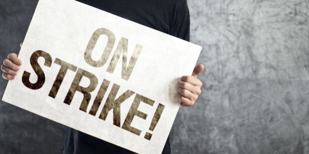 Man holding banner with ON STRIKE printed protest message.