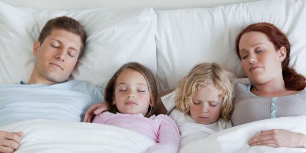 Adorable young family sleeping in the bed together