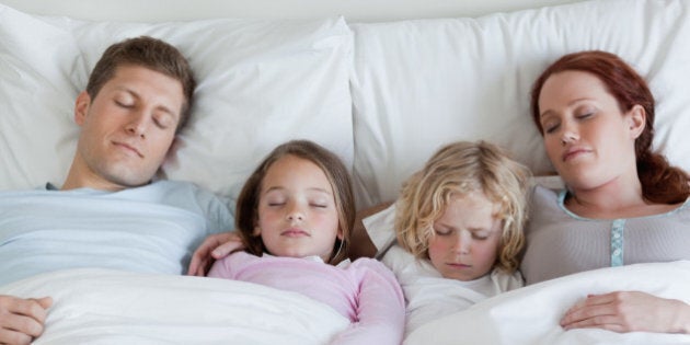 Adorable young family sleeping in the bed together