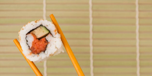 Woman holding sushi by chopsticks