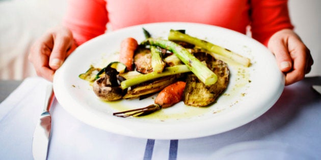 Woman holding plate of grilled vegetables in a restaurant