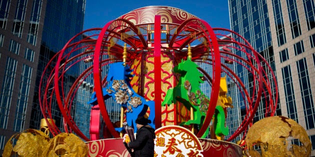 A worker walks by a Lunar New Year decoration displayed outside a shopping mall in Beijing Wednesday, Jan. 8, 2014. Chinese will celebrate the Lunar New Year on Feb. 1 this year which marks the Year of Horse on the Chinese zodiac. (AP Photo/Andy Wong)