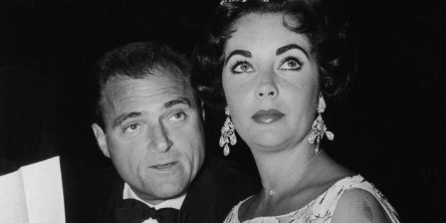 British-born actor Elizabeth Taylor sits with her third husband, American film producer Mike Todd (1909 - 1958), at a Golden Globe Awards ceremony at the Coconut Grove nightclub, Hollywood, California, 1957. (Photo by Hulton Archive/Getty Images)