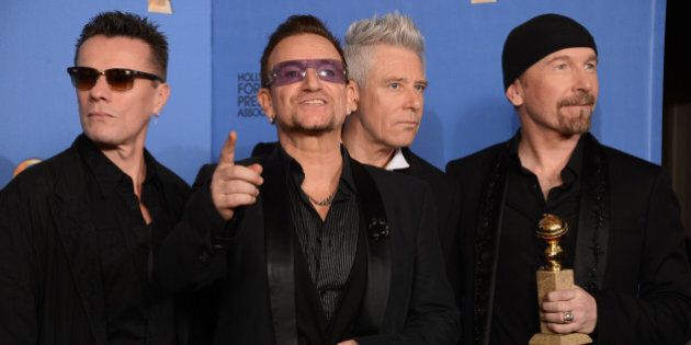 From left, Larry Mullen Jr., Bono, Adam Clayton, and The Edge of U2 pose in the press room with the award for best original song for