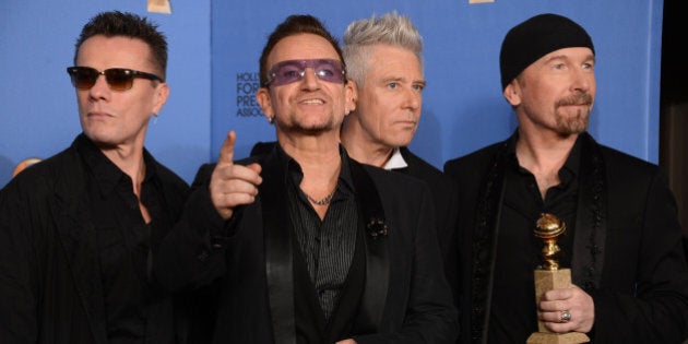 From left, Larry Mullen Jr., Bono, Adam Clayton, and The Edge of U2 pose in the press room with the award for best original song for