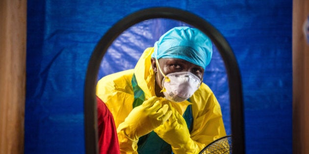 FILE - In this Thursday, Oct. 16, 2014 file photo, a healthcare worker dons protective gear before entering an Ebola treatment center in the west of Freetown, Sierra Leone. (AP Photo/Michael Duff, File)