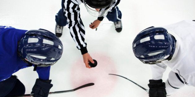Directly above shot of referee and two ice hockey players in face-off