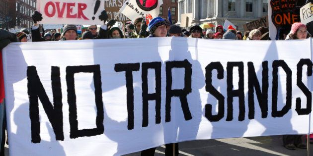 Protesters from across New England hold signs during a rally against the possibility of so-called tar sands oil being piped in from Montreal, in Portland, Maine, U.S., on Saturday, Jan. 26, 2013. The Associated Press reported that environmental groups say plans are in the works to bring oil by pipeline from western Canada to Montreal and then to Portland. Critics say tar sands, or oil sands, oil is so corrosive, acidic and thick that it's more likely to spill than conventional crude oil and that would put rivers, lakes and streams at risk in Maine, New Hampshire and Vermont, according to AP. Photographer: Bizuayehu Tesfaye/Bloomberg via Getty Images