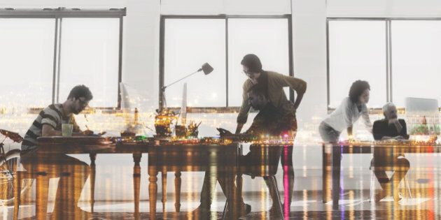 Multiple exposure shot of colleagues working in a modern office superimposed over a city background