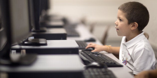 Six year old boy learns the keyboard during a computer class.