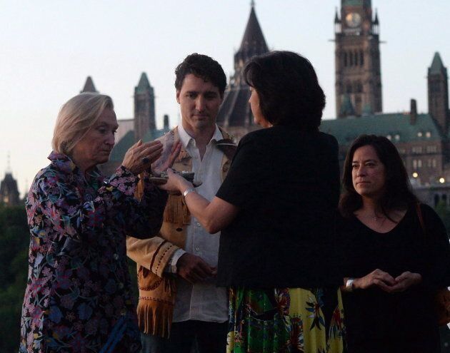 Prime Minister Justin Trudeau looks on as he is joined by Indigenous and Northern Affairs Minister Caroly Bennett, left, and Minister of Justice and Attorney General of Canada Jody Wilson-Raybould, right, as they take part in the National Aboriginal Day Sunrise Ceremony on the banks of the Ottawa River in Gatineau, Quebec on June 21, 2016.