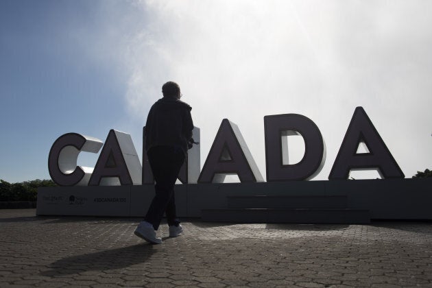 A tourist walks towards a 'Canada 150' sign in Niagara Falls, Ont., on June 21, 2017.