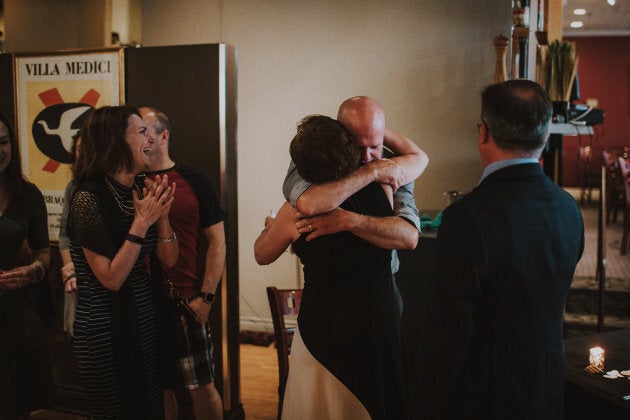 Eric, the father of the bride, sharing a hug with Jackie, the mother of the groom, as Karen, the stepmother of the bride, and Troy, the father of the groom, watch on.