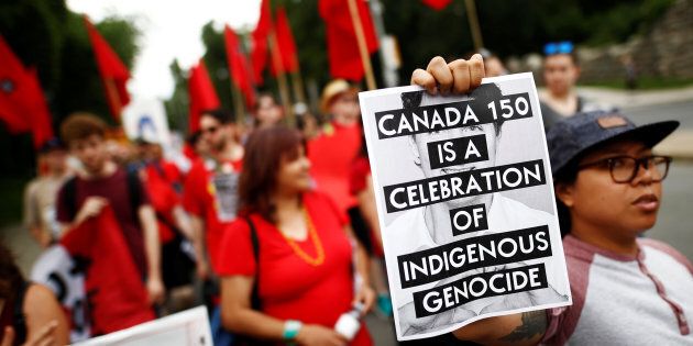 An indigenous rights activist holds a sign reading