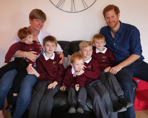 Oliver Rooney (L), his mom and brothers posing with Prince Harry. (Photo by Nigel Roddis/Getty Images)