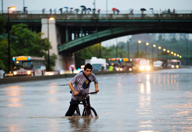 A man rides his bicycle during a flood on the Don Valley Parkway, a major highway, during a heavy rainstorm in Toronto, July 8, 2013.