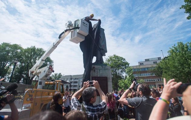A Halifax City staff member covers the Edward Cornwallis statue with a black tarp as activists protest in Cornwallis Park in Halifax on Saturday, July 15, 2017.