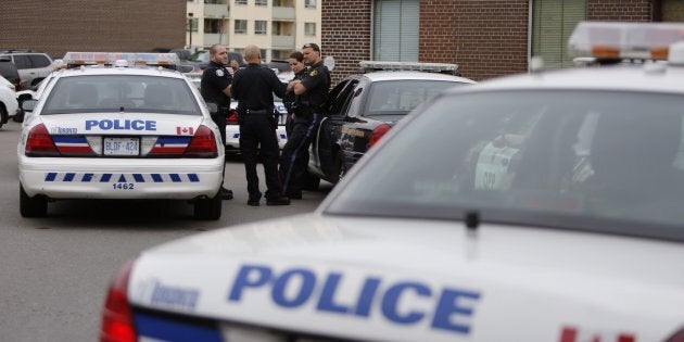 More than a dozen police cars including O.P.P. wait in a booking line at Toronto Police 41 Division. Dawn raids target two rival gangs in broad swath, arresting more than 50 suspects, May 27, 2014.