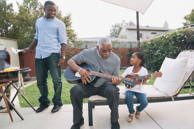 African American grandfather teaching granddaughter to play guitar