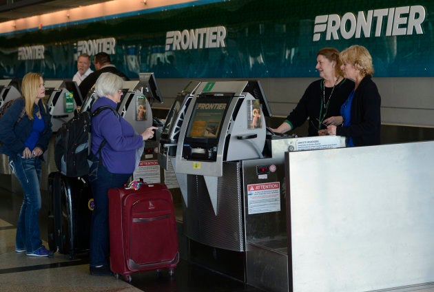 Frontier Airlines customer service agents help customers at the ticket counter at Denver International Airport on Jan. 16, 2015.