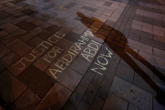 A man casts a shadow near a message written in chalk during a vigil for Abdirahman Abdi in Ottawa, July 26, 2016.