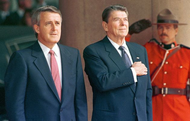 Former U.S. President Ronald Reagan (right) stands with former Canadian Prime Minister Brian Mulroney (left) and an officer from the RCMP as he arrives at the annual G7 Summit in Toronto in this June 19, 1988 file photo. Mulroney and Reagan negotiated the original Canada-U.S. Free Trade Agreement.
