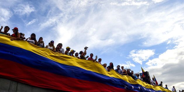 Opposition activists hold a large Venezuelan flag during a protest in Caracas, on July 24, 2017.
