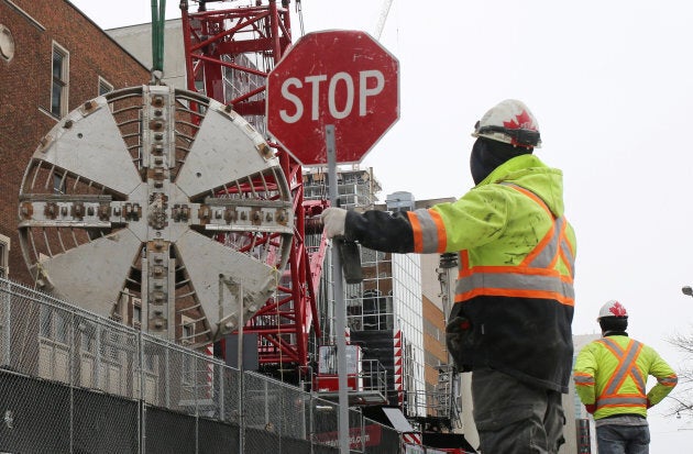 Workmen watch as a cutting head of a tunnel boring machine is lifted from the underground construction site of the Eglinton Crosstown light rail transit (LRT) project in Toronto, Ont., March 13, 2017.