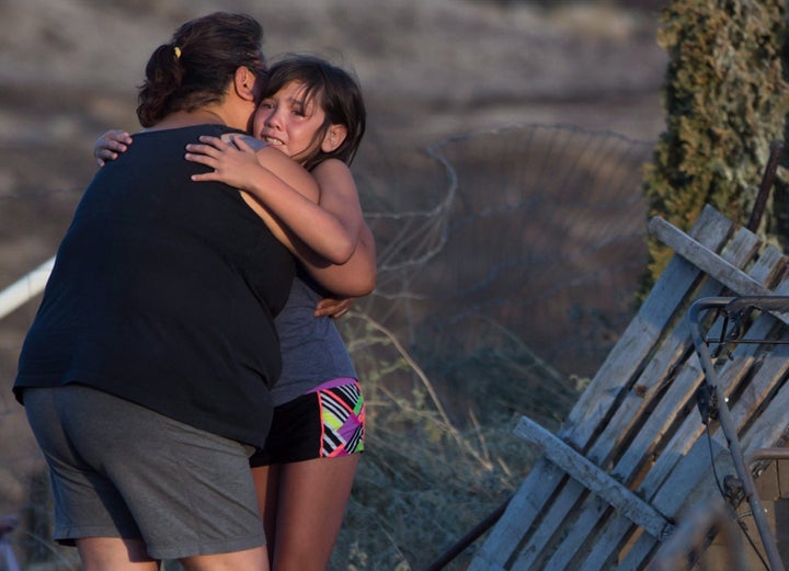 Nevaeh Porter, 8, is comforted by her grandmother Angie Thorne as they view the remains of their home that was destroyed by wildfire on the Ashcroft First Nation, near Ashcroft, B.C., late Sunday July 9, 2017.