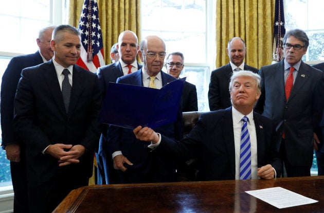 U.S. President Donald Trump smiles after announcing a permit for TransCanada Corp's Keystone XL oil pipeline while TransCanada Chief Executive Officer Russell Girling (L), U.S. Commerce Secretary Wilbur Ross (C) and U.S. Energy Secretary Rick Perry (R) stand beside him in the Oval Office of the White House in Washington, U.S., March 24, 2017.