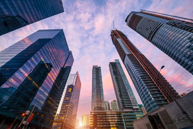 Low angle view of compact modern skyscrapers in busy Toronto downtown district during sunset.