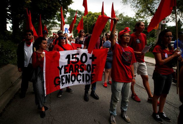 Indigenous rights activists hold a sign reading "150 + Years of Genocide", as they march following the "Unsettle Canada Day 150 Picnic", as the country marks its 150th anniversary with "Canada 150" celebrations, in Toronto, Ont., July 1, 2017.